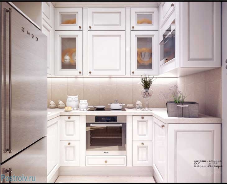 Очень маленькая белая кухня с серебристым холодильником. Фото