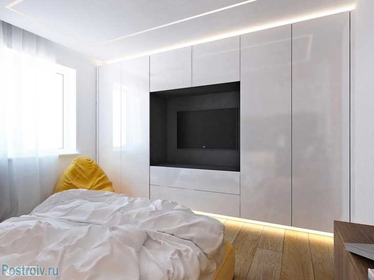 Белый глянцевый шкаф в спальне с вырезом для телевизора. Фото