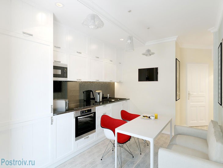 Белые стены и красные акцентные стулья на кухне. Фото